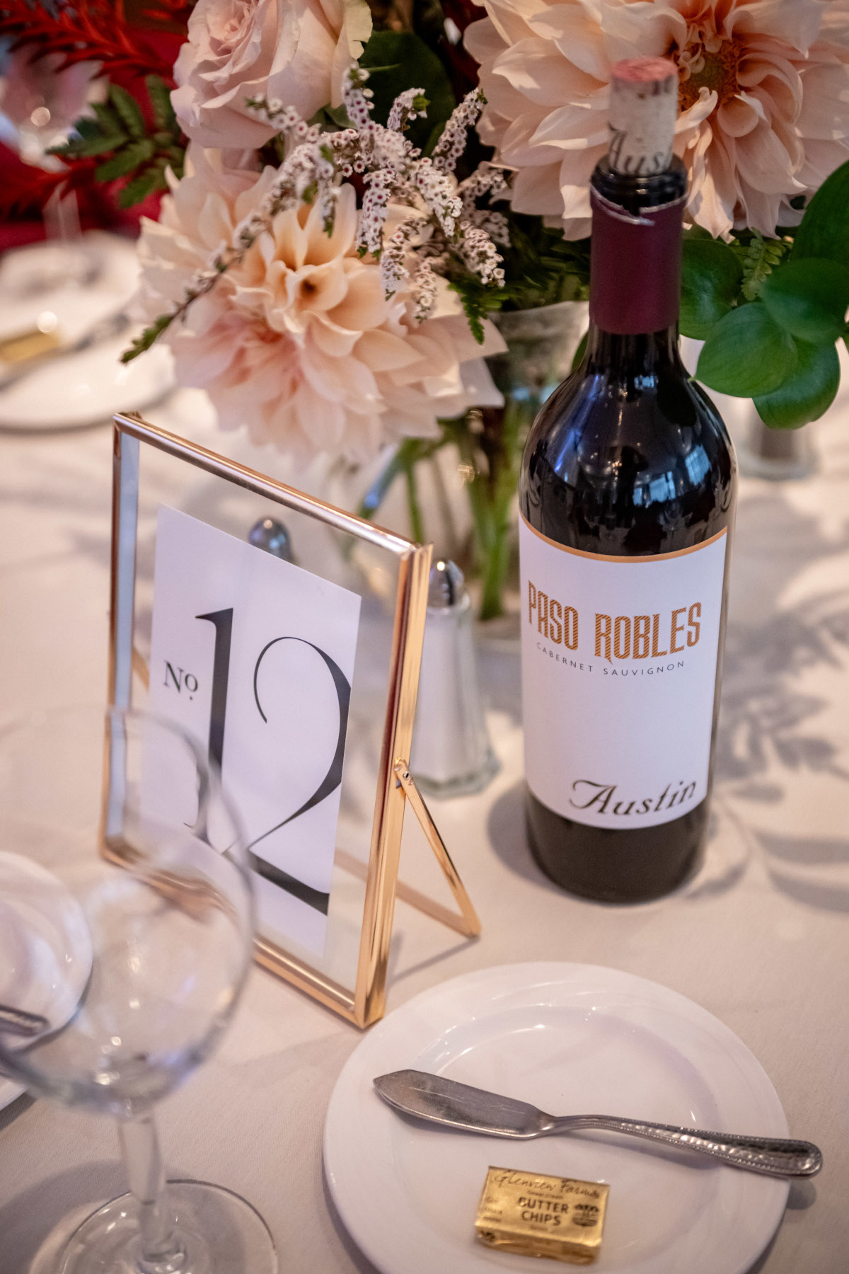 Gorgeous close-up of floral centerpiece, wine bottle, and elegant table number card